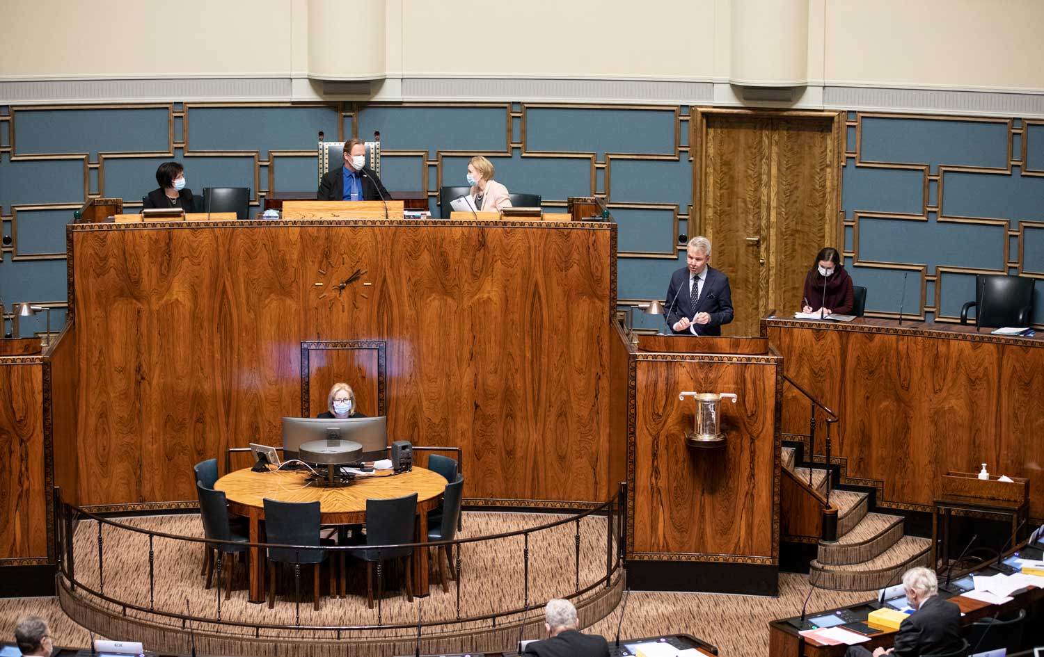 Ulkoministeri Pekka Haavisto eduskunnan istuntosalin puhujapöntössä puhemiehistön ja muiden ministerien istuessa hänen takanaan.