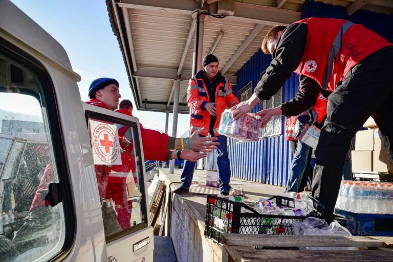 Punaisen Ristin avustustyöntekijät purkavat ruoka-apua autosta Ukrainassa.