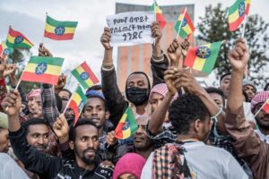 Mielenosoittajat heiluttavat Etiopian lippuja ja tekstiä kylttiä.