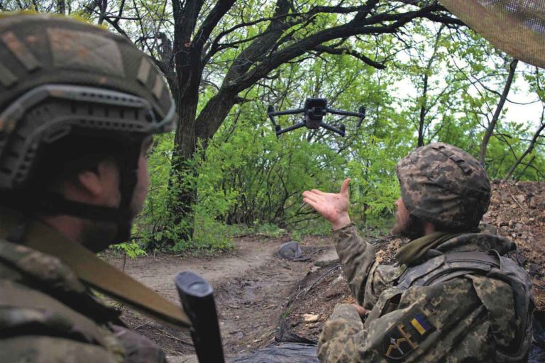 Kaksi ukrainalaista sotilasta metsässä. Heistä toinen lähettää ilmaan lennokin.