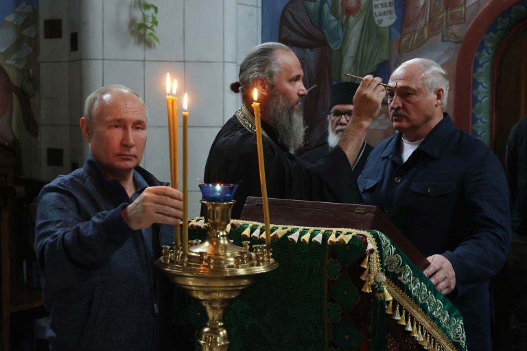 Putin asettaa palavan tuohuksen Valamon luostarissa. Taustalla Lukashenka.