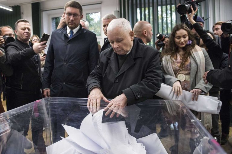 Jaroslaw Kaczynski drops his vote to a ballot while media films the voting.