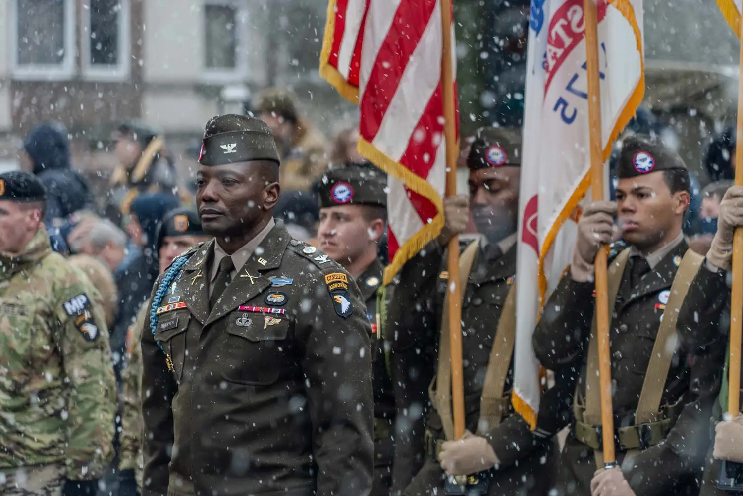 Yhdysvaltalaissotilaita muodossa lippujen kanssa lumen sataessa.