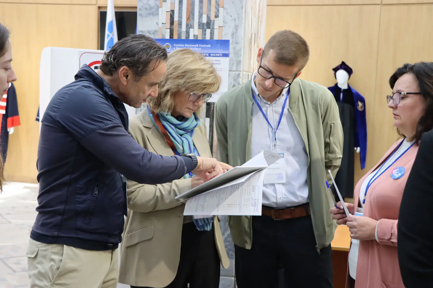 Neljä henkeä tarkastelee asiakirjoja vaalipaikalla.
