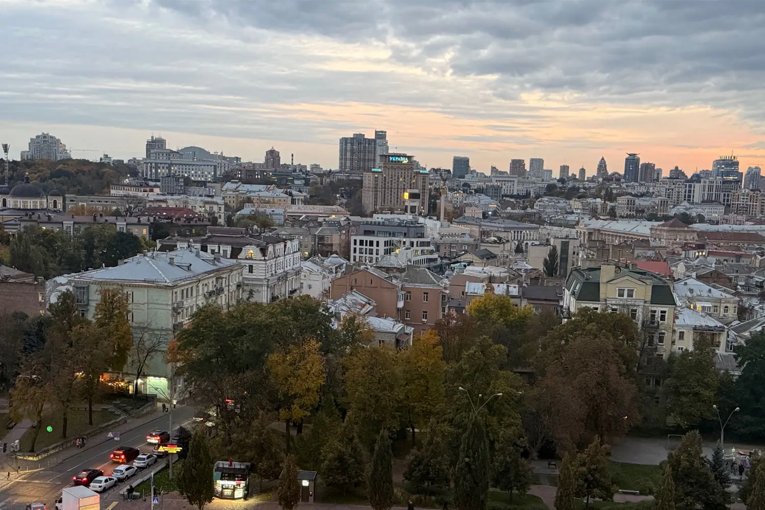 Kuvassa näkymä parvekkeelta Kiovan kaupunkiin iltaruskossa. Alhaalla autoja jonossa.